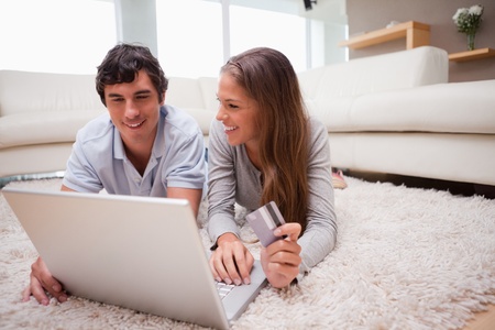 Young couple lying on the floor shopping onlineの写真素材