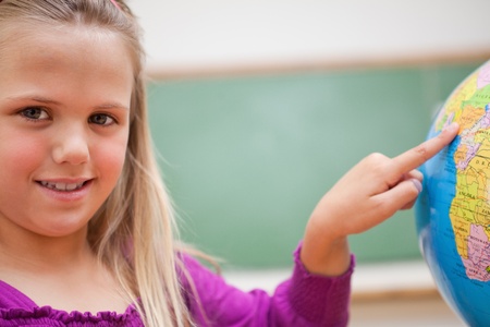 Close up of a schoolgirl pointing at a country on a globeの写真素材