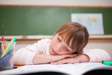 Schoolgirl sleeping on a desk in a classroomの写真素材