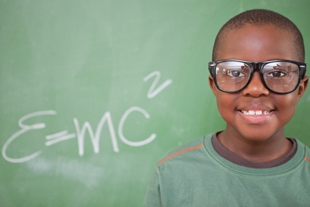 Smart schoolboy posing in front of a blackboard