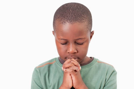 Young boy praying against a white backgroundの写真素材