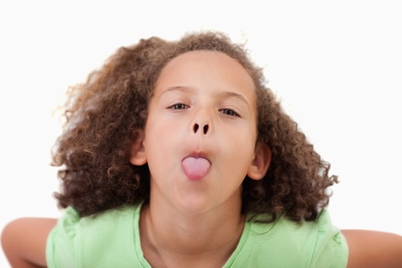 Cute girl sticking out her tongue against a white backgroundの写真素材