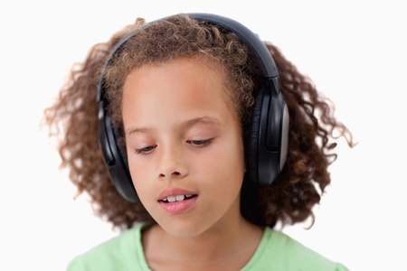 Young girl listening to music against a white backgroundの写真素材