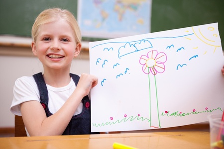 Girl showing her drawing in a classroomの写真素材