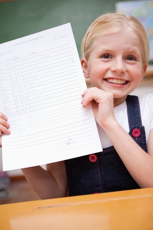 Portrait of a girl showing her school report in a classroomの写真素材