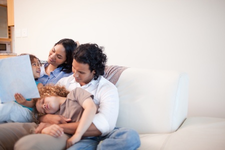 Young family in the living room looking at photo album togetherの写真素材