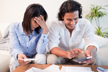 Young couple checking their bills in the living roomの写真素材