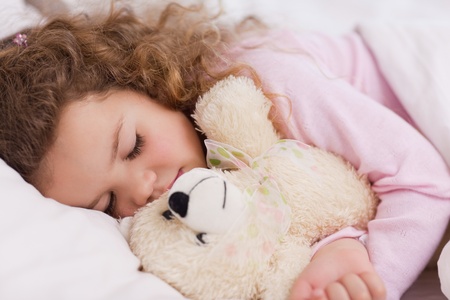 Little girl hugging her teddy while sleepingの写真素材