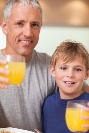 Close up of a boy and his father having breakfast in a kitchenの写真素材