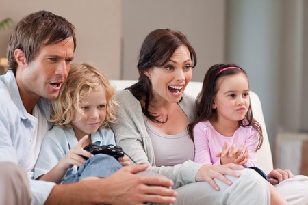 Cheerful family playing video games together in a living roomの写真素材