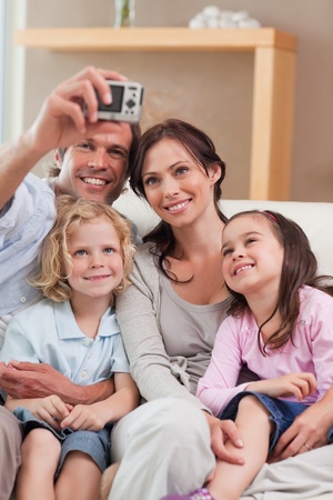 Portrait of a happy father taking a picture of his family in a living roomの写真素材