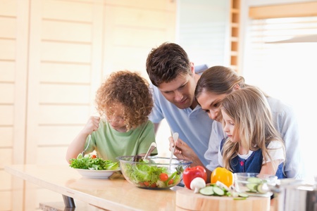 Family preparing a salad together in their kitchenの写真素材