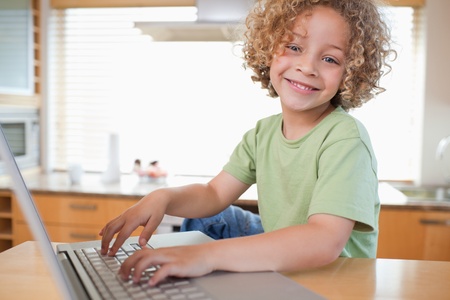 Boy using a laptop in a kitchenの写真素材