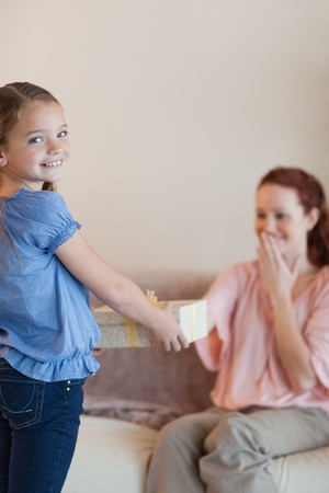 Little girl giving her surprised mother a presentの写真素材