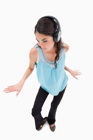 Portrait of a happy woman dancing while listening to music against a white backgroundの写真素材