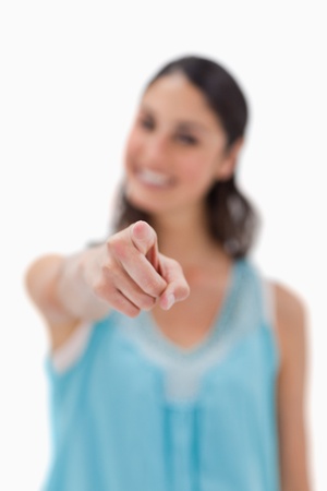 Portrait of a smiling woman pointing at the viewer against a white backgroundの写真素材