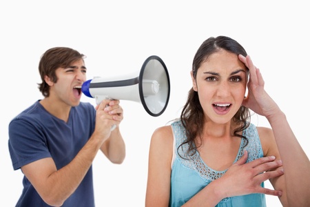 Man shouting at her girlfriend through a megaphone against a white backgroundの写真素材