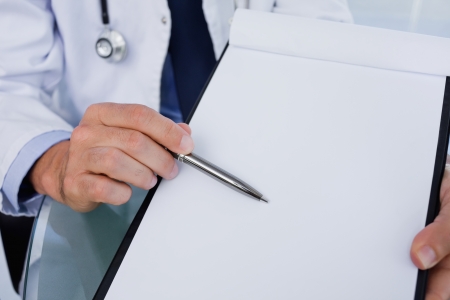 Close up of a male doctor showing a blank document in an officeの写真素材
