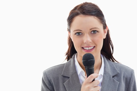 Close-up of a businesswoman holding a microphone against white backgroundの写真素材