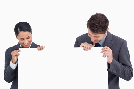 Close up of salesteam looking at blank sign in their hands against a white backgroundの写真素材