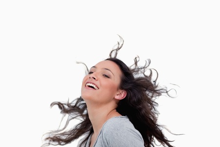 Smiling woman flipping her hair against a white backgroundの写真素材