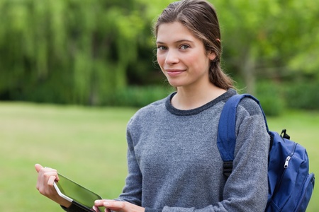 Smiling young woman holding a tablet computer while standing in the countrysideの写真素材