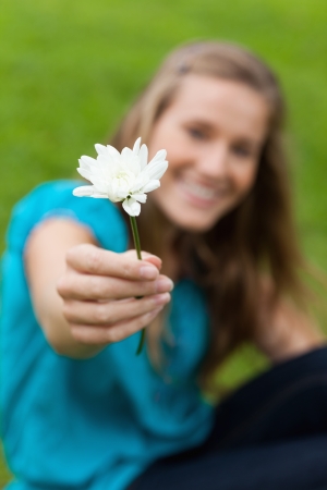 Beautiful white flower held by a smiling young girl in a parkの写真素材