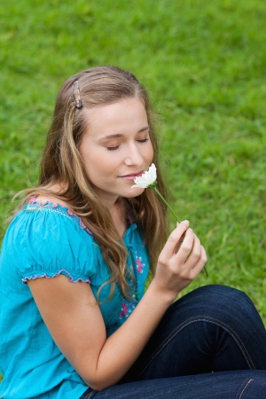 Young relaxed girl smelling a beautiful white flower while closing her eyesの写真素材