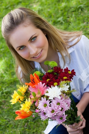 Attractive blonde teenage girl holding a beautiful bunch of flower in the countrysideの写真素材