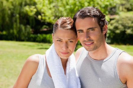 Woman with a white towel around her neck standing with a smiling man in workout gearの写真素材