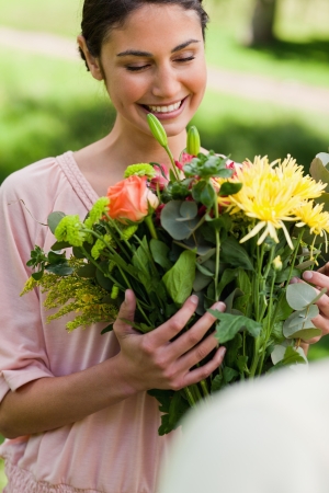 Woman smiling as she looks at a bouquet flowers which have been given to her a friendの写真素材