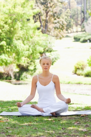 Young woman sitting in a yoga position on the grassの写真素材