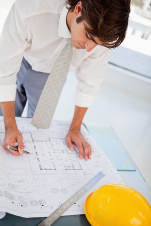 A man with a pen in hand is hard at work on some blueprints for workの写真素材