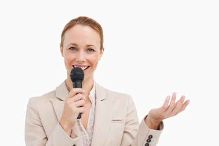 Portrait of a businesswoman speaking with a microphone against white backgroundの写真素材