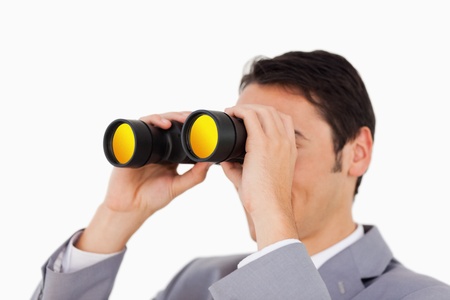 Man in a suit using binoculars against white backgroundの写真素材