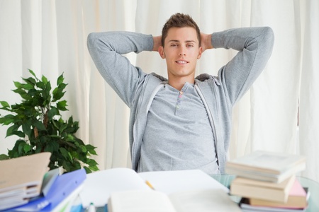Portrait of a student stretching while looking away in front of his homeworkの写真素材