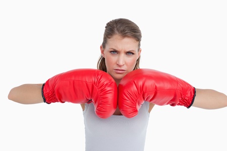 Serious woman with boxing gloves against a white backgroundの写真素材