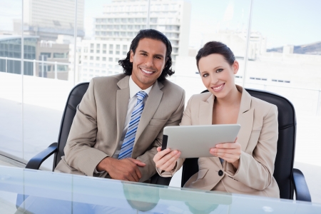Cheerful business team using a tablet computer in an officeの写真素材