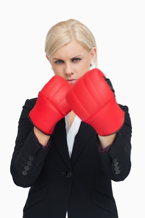 Serious businesswoman wearing red boxing gloves against white backgroundの写真素材