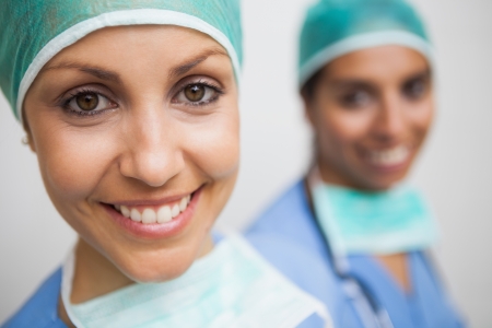 Smiling nurse in surgical cap with other smiling nurse in background