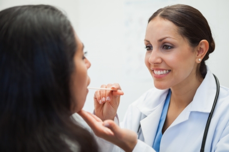 Womans mouth being examined by happy doctor in hospital roomの写真素材