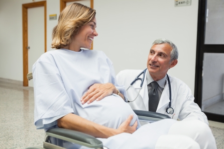 Doctor is talking to a pregnant woman in hospital corridorの写真素材