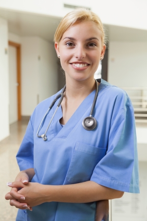 Smiling nurse leaning against stairwell in hospital corridorの写真素材