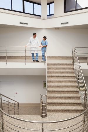 Nurse and doctor talking at top of hospital stairwellの写真素材