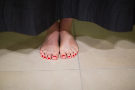 Womans feet behind changing room curtain in shopping mall