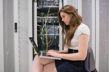 Female technician doing data storage with the laptop in data center