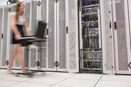 Woman pushing computer through data center beside the servers