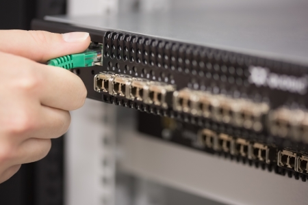 Woman plugging USB cable into server in data center