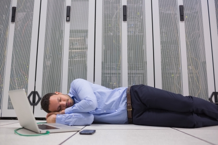 Man sleeping while doing maintenance on servers with laptop