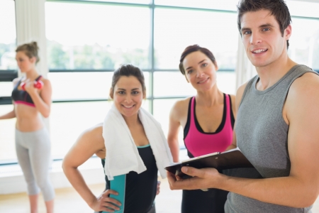 Trainer and women smiling in fitness studioの写真素材